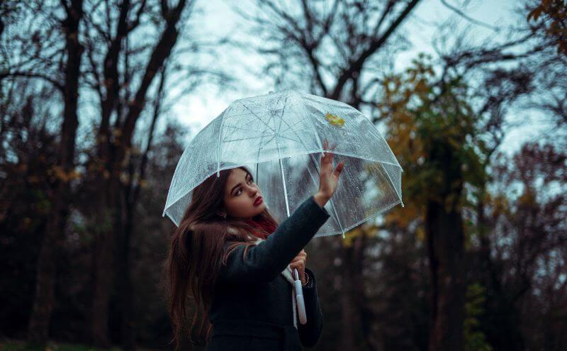 a woman has an umbrella and looking at a leaf