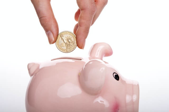 putting a coin into piggy bank