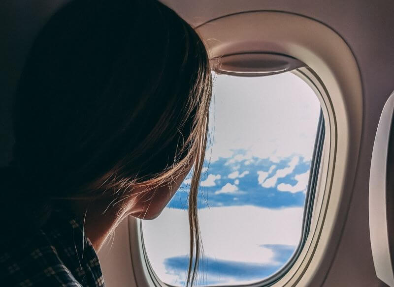 A woman watching outside from the window of the airplane